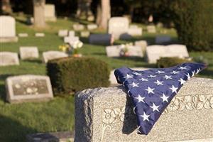 American flag folded over a gravestone in a cemetery.